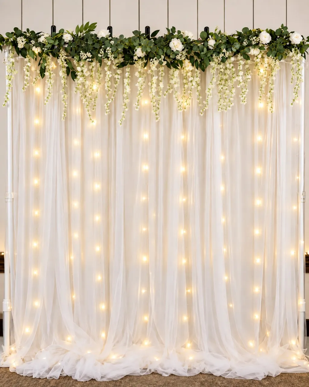 Fairytale Wedding photobooth backdrop with ivory draping, greenery, and warm lights